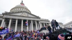 FILE - Rioters loyal to U.S. President Donald Trump swarm the U.S. Capitol in Washington, Jan. 6, 2021. Jason Donner, a former Fox News producer, says in a lawsuit that he was fired for pushing back against false claims about the riot.