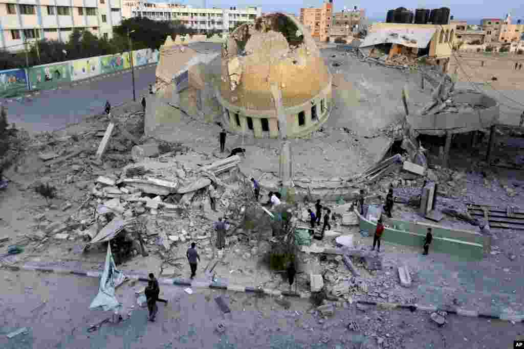 People stand outside a mosque destroyed in an Israeli air strike in Khan Younis, Gaza Strip, Oct. 8, 2023.