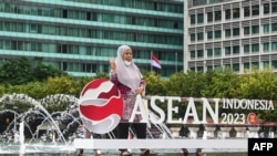 Seorang ibu berpose di dekat logo Association of Southeast Asian Nations (ASEAN), usai upacara peresmian Indonesia sebagai ketua ASEAN untuk 2023, di Jakarta, 29 Januari 2023. (Foto:Goh Chai Hin / AFP)