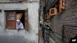 A Kashmiri woman looks on as a paramilitary soldier guard during the door-to -door election campaigning by Bharatiya Janata Party candidate ahead of the Jammu and Kashmir state assembly elections, in Srinagar, Indian controlled Kashmir, Aug. 29, 2024.