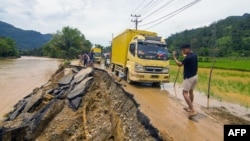 A man guides a truck along an erosion-damaged road following flash flooding in Pesisir Selatan Regency, West Sumatra, Indonesia, on March 9, 2024.