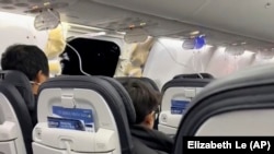 This image from video provided by Elizabeth Le shows passengers near the damage on an Alaska Airlines Boeing 737 Max 9, Flight 1282, which was forced to return to Portland International Airport, Jan. 5, 2024. (Elizabeth Le via AP)