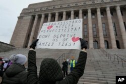 Masyarakat, sebagian besar etnis Rusia, berkumpul di depan gedung parlemen Finlandia untuk memprotes penutupan titik perlintasan perbatasan dengan Rusia, di Helsinki, Finlandia, Sabtu, 18 November 2023. (AP/Sergei Grits)