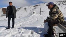 FILE - Farmer Erkinbek Kaldanov, right, and the Syn-Tash district chief Maksat Dzholdoshev, is seen near the artificial glacier in a mountain gorge near the village of Syn-Tash, Kyrgyzstan, Feb. 13, 2024.