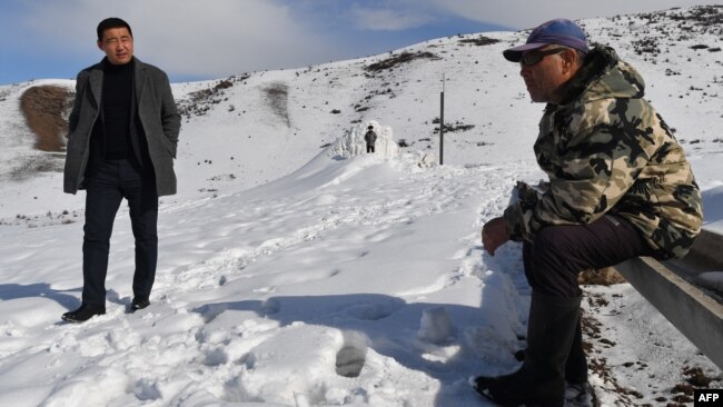 FILE - Farmer Erkinbek Kaldanov, right, and the Syn-Tash district chief Maksat Dzholdoshev, is seen near the artificial glacier in a mountain gorge near the village of Syn-Tash, Kyrgyzstan, Feb. 13, 2024.