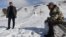 FILE - Farmer Erkinbek Kaldanov, right, and the Syn-Tash district chief Maksat Dzholdoshev, is seen near the artificial glacier in a mountain gorge near the village of Syn-Tash, Kyrgyzstan, Feb. 13, 2024.