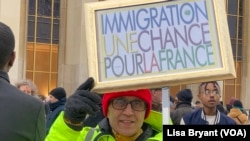 Seorang demonstran keturunan Algeria membawa poster bertuliskan "Imigrasi adalah kesempatan bagi Prancis" dalam aksi protes menentang undang-undang migrasi Prancis di Paris pada 21 Januari 2024. (Foto: VOA/Lisa Bryant)