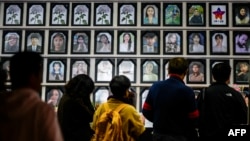 Orang-orang memberi penghormatan di depan foto korban saat menghadiri acara peringatan insiden Halloween di Seoul pada 29 Oktober 2023. Acara itu memperingati ulang tahun aksi massa yang menewaskan 159 orang di Itaewon setahun sebelumnya. (Foto: AFP)
