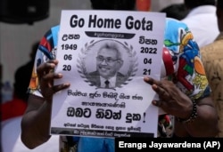 FILE - A protestor holds a poster designed as a death notification of Sri Lankan President Gotabaya Rajapaksa at the ongoing protest site outside the president's office in Colombo, Sri Lanka, Thursday, April 21, 2022. (AP Photo/Eranga Jayawardena, File)