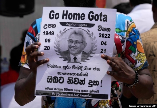 FILE - A protestor holds a poster designed as a death notification of Sri Lankan President Gotabaya Rajapaksa at the ongoing protest site outside the president's office in Colombo, Sri Lanka, Thursday, April 21, 2022. (AP Photo/Eranga Jayawardena, File)