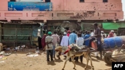 People gather by a medical center building riddled with bullet holes at the Souk Sitta (Market Six) in the south of Khartoum on June 1, 2023.