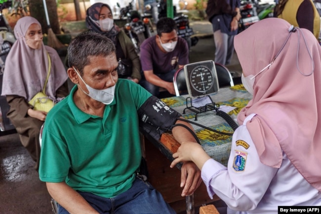 Seorang petugas kesehatan melakukan pemeriksaan kesehatan terhadap seorang pria sebelum memberikan vaksinasi COVID-19 di puskesmas di Jakarta, 1 Februari 2023. (Foto: Bay Ismoyo/AFP)