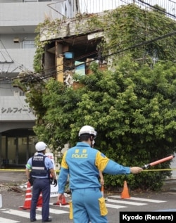 日本西南部宫崎市的警察站在被地震毁坏的建筑物旁警戒。（2024年8月8日）