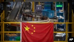 A Chinese flag hangs near an automated parcel handling line at a warehouse for an online retailer in Beijing, Nov. 11, 2020. (AP/Mark Schiefelbein)