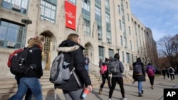 FILE - Students walk past an entrance to Boston University College of Arts and Sciences in Boston, Nov. 29, 2018.