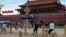 A security person watch over residents passing in front of Tiananmen Gate in Beijing, June 4, 2023.