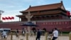 A security person watch over residents passing in front of Tiananmen Gate in Beijing, June 4, 2023.