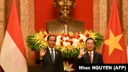 Presiden Joko Widodo (Kiri) dan Presiden Vietnam Vo Van Thuong (kanan) melambai saat pertemuan di Istana Kepresidenan di Hanoi pada 12 Januari 2024. (Foto: AFP/Nhac NGUYEN)