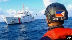 FILE - In this handout photo provided by the Philippine Coast Guard, members of the Philippine Coast Guard patrol at Whitsun Reef, South China Sea, April 14, 2021. 