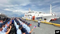 Personel Penjaga Pantai Filipina mengibarkan bendera Vietnam dan Filipina untuk menyambut kedatangan kapal Penjaga Pantai Vietnam (VCG), CSB 8002, di Manila, Filipina, Senin, 5 Agustus 2024. (Joeal Calupitan/AP)