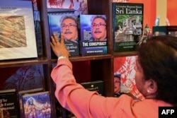 Seorang perempuan melihat salinan buku 'The Conspiracy' yang ditulis oleh presiden terguling Sri Lanka Gotabaya Rajapaksa yang dipajang di sebuah toko buku di Kolombo, 7 Maret 2024. (Ishara S.KODIKARA/AFP)