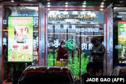 Seorang pekerja restoran Korea Utara (Kiri) berdiri di pintu masuk sebuah restoran di Shenyang, Provinsi Liaoning, China, 31 Maret 2023. (Foto: AFP/JADE GAO)