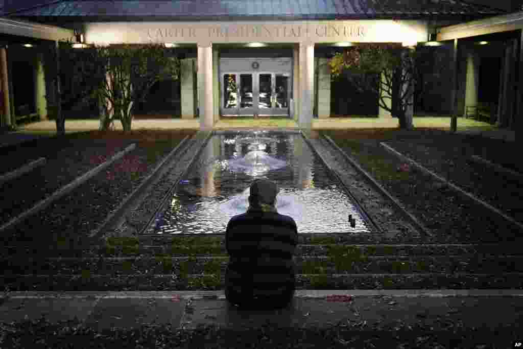 Royce Soble, of Atlanta, sits near a reflection pool at The Carter Center in Atlanta after the announcement that former first lady Rosalynn Carter had died, Sunday, Nov. 19, 2023. (AP Photo/Brynn Anderson)