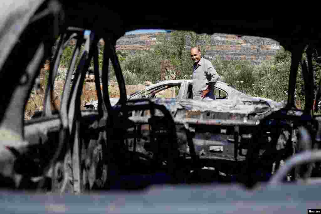 A Palestinian man checks burned vehicles after an attack by Israeli settlers near Ramallah in the Israeli-occupied West Bank.