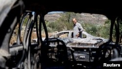 A Palestinian man checks burned vehicles after an attack by Israeli settlers near Ramallah in the Israeli-occupied West Bank.