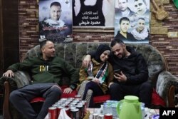 Asil al-Titi, center, a 23-year-old former prisoner from the occupied West Bank, sits between her two brothers on Nov. 25, 2023 at the family home in Balata refugee camp after her release from Israeli jail in exchange for hostages held in Gaza by Hamas.