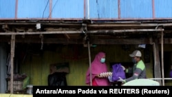 Seorang relawan menyerahkan bantuan sembako gratis kepada seorang perempuan, di tengah wabah COVID-19 di Sulawesi, 20 April 2020, sebagai ilustrasi. (Foto: Antara/Arnas Padda via REUTERS)