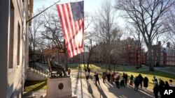 FILE - People take photographs near a John Harvard statue, Jan. 2, 2024, on the campus of Harvard University, in Cambridge, Mass.