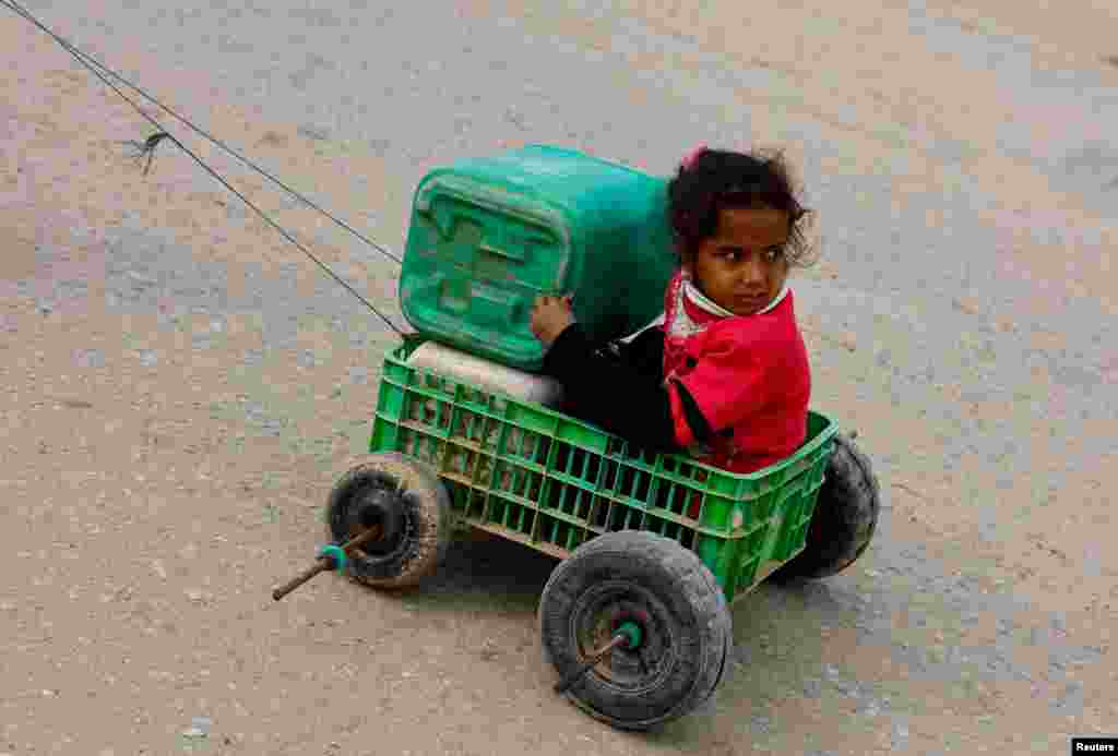 A girl sits in a makeshift cart as Palestinians wait to receive food amid shortages of food supplies in Rafah in the southern Gaza Strip. REUTERS/Mohammed Salem