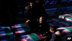 A woman mourns over the flag-draped coffin of a loved one who was killed in a Jan. 3, 2024, bomb explosion, during the victims' funeral ceremony in the city of Kerman about 820 kilometers southeast of the capital Tehran, Iran, Jan. 5, 2024. 