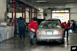 FILE - Workers wash a car in Chicago, April 10, 2024. U.S. hiring decelerated sharply in July in the face of high interest rates as employers added just 114,000 jobs.