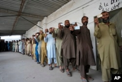 Immigrants, mostly Afghans, show their ID cards as they wait their turn to verify data at a counter of Pakistan's National Database and Registration Authority, in Karachi, Pakistan, Nov. 7, 2023.