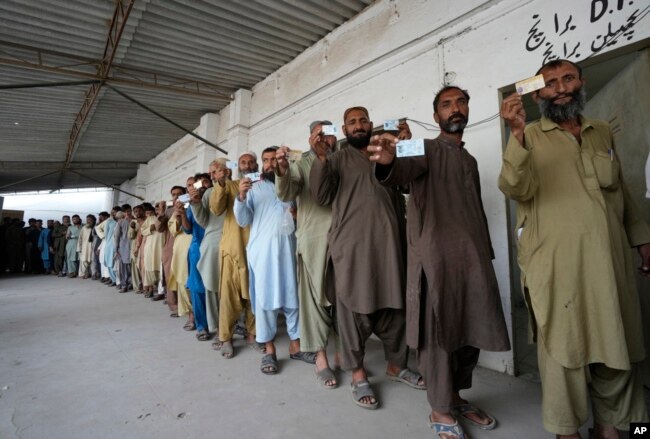 Immigrants, mostly Afghans, show their ID cards as they wait their turn to verify data at a counter of Pakistan's National Database and Registration Authority, in Karachi, Pakistan, Nov. 7, 2023.