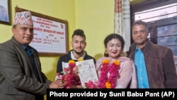 Same-sex couple Surendra Pandey, 2nd left, and Maya Gurung, pose for a photograph with their marriage registration certificate at Dorje village council office, located in the mountains west of Kathmandu, Nepal, Nov. 29, 2023.