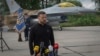 FILE - Ukraine's President Volodymyr Zelenskyy answers reporters' questions with a Ukrainian Air Force F-16 fighter jet in the background, in an undisclosed location in Ukraine, Aug. 4, 2024.