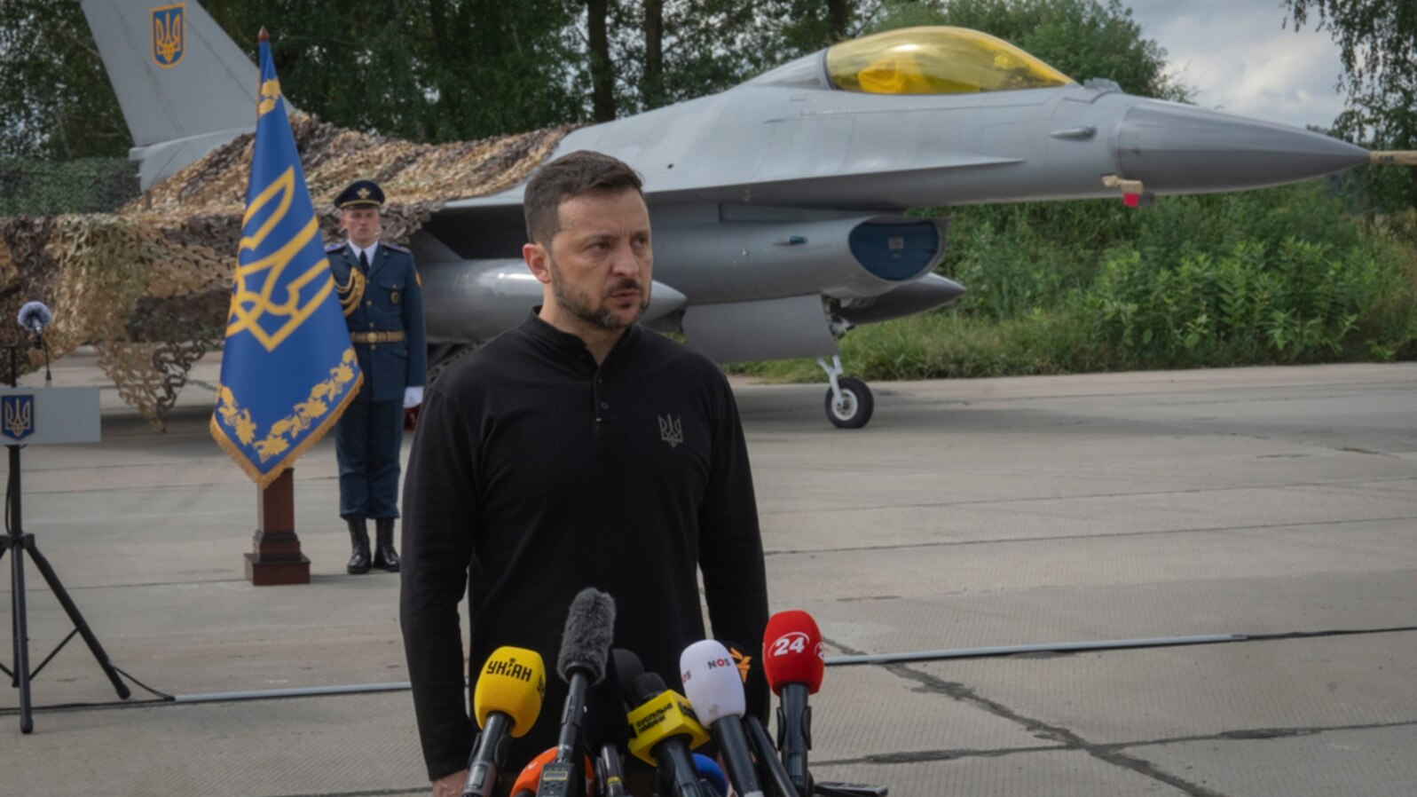 FILE - Ukraine's President Volodymyr Zelenskyy answers reporters' questions with a Ukrainian Air Force F-16 fighter jet in the background, in an undisclosed location in Ukraine, Aug. 4, 2024.