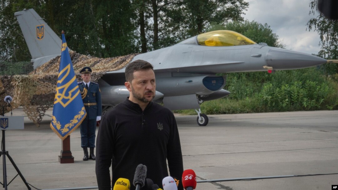 Tổng thống Ukraine Volodymyr Zelenskyy trả lời câu hỏi của phóng viên đứng trước máy bay chiến đấu F-16 của Không quân Ukraine tại một địa điểm không được tiết lộ ở Ukraine, ngày 4 tháng 8 năm 2024.
