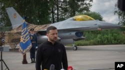 Presiden Ukraina Volodymyr Zelenskyy menjawab pertanyaan wartawan sambil berdiri di depan jet tempur F-16 Angkatan Udara Ukraina di lokasi yang dirahasiakan di Ukraina, 4 Agustus 2024. (Foto: AP)