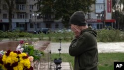 A servicewomen cries in Kherson, Ukraine, as she leaves flowers to commemorate those killed in Russia's war on Ukraine, Nov. 11, 2023. Residents of the city of Kherson are marking one year since Ukraine retook it from occupying Russian forces.