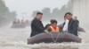 This recent undated photo released by North Korea's official Korean Central News Agency via KNS on July 31, 2024, shows North Korea's leader, Kim Jong Un, left, riding through flood waters after record-breaking rain in the city of Sinuiju. 