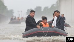 This recent undated photo released by North Korea's official Korean Central News Agency via KNS on July 31, 2024, shows North Korea's leader, Kim Jong Un, left, riding through flood waters after record-breaking rain in the city of Sinuiju. 