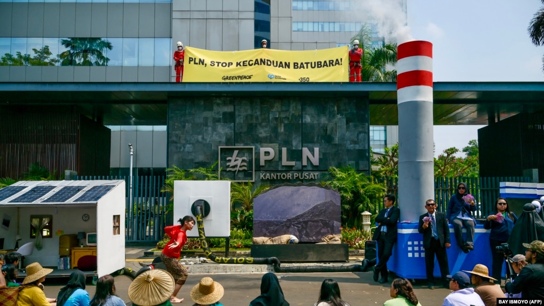Aktivis lingkungan menggelar aksi teatrikal dan membentangkan spanduk bertuliskan 'PLN, berhenti kecanduan batu bara' sebagai protes terhadap kebijakan PLN terhadap batu bara di Jakarta pada 26 Oktober 2023. (Foto: BAY ISMOYO/AFP)