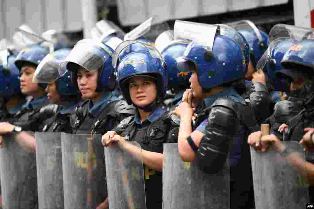 Policewomen in riot gear wait for women activists during a protest to mark International Women's Day in Manila, Philippines.