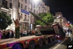 Anggota kompi militer Grup Wagner memuat tank mereka ke truk di sebuah jalan di Rostov-on-Don, Rusia, 24 Juni 2023, sebelum meninggalkan area di markas Distrik Militer Selatan. (Foto: AP)