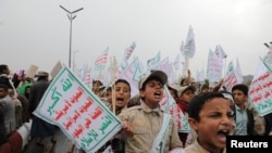 Children hold signs, as supporters of the Houthi rally to denounce the U.S. labeling of Houthis as a 'Specially Designated Global Terrorist' group, in Sanaa, Yemen Jan. 19, 2024.