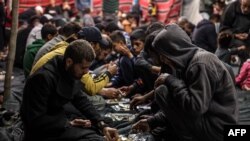 FILE—Palestinians share an iftar meal, the breaking of fast, on the first day of the Muslim holy fasting month of Ramadan, at a camp for displaced people in Rafah in the southern Gaza Strip on March 11, 2024.